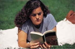 young girl outside on blanket reading